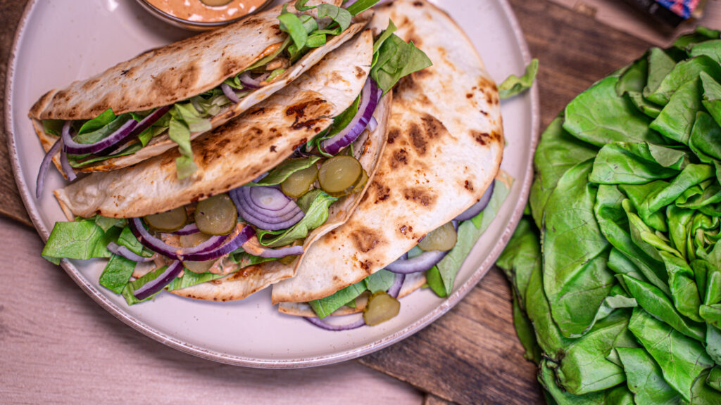Trei Cheeseburger Taco de Curcan gata de servire, așezate pe o farfurie, alături de salată verde.