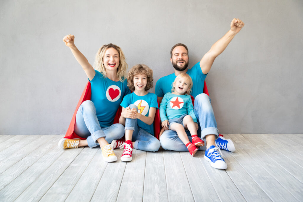 Familie zâmbitoare în costume de supereroi, simbolizând părinții care oferă copiilor lor o creștere sănătoasă cu ajutorul cărnii de curcan de la Peneș Curcanul.