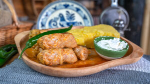 Sarmale tradiționale românești, preparate cu carne tocată de curcan, în foi de varză murată, servite alături de mămăligă aurie și smântână cremoasă, pe un platou rustic, cu decor autentic.